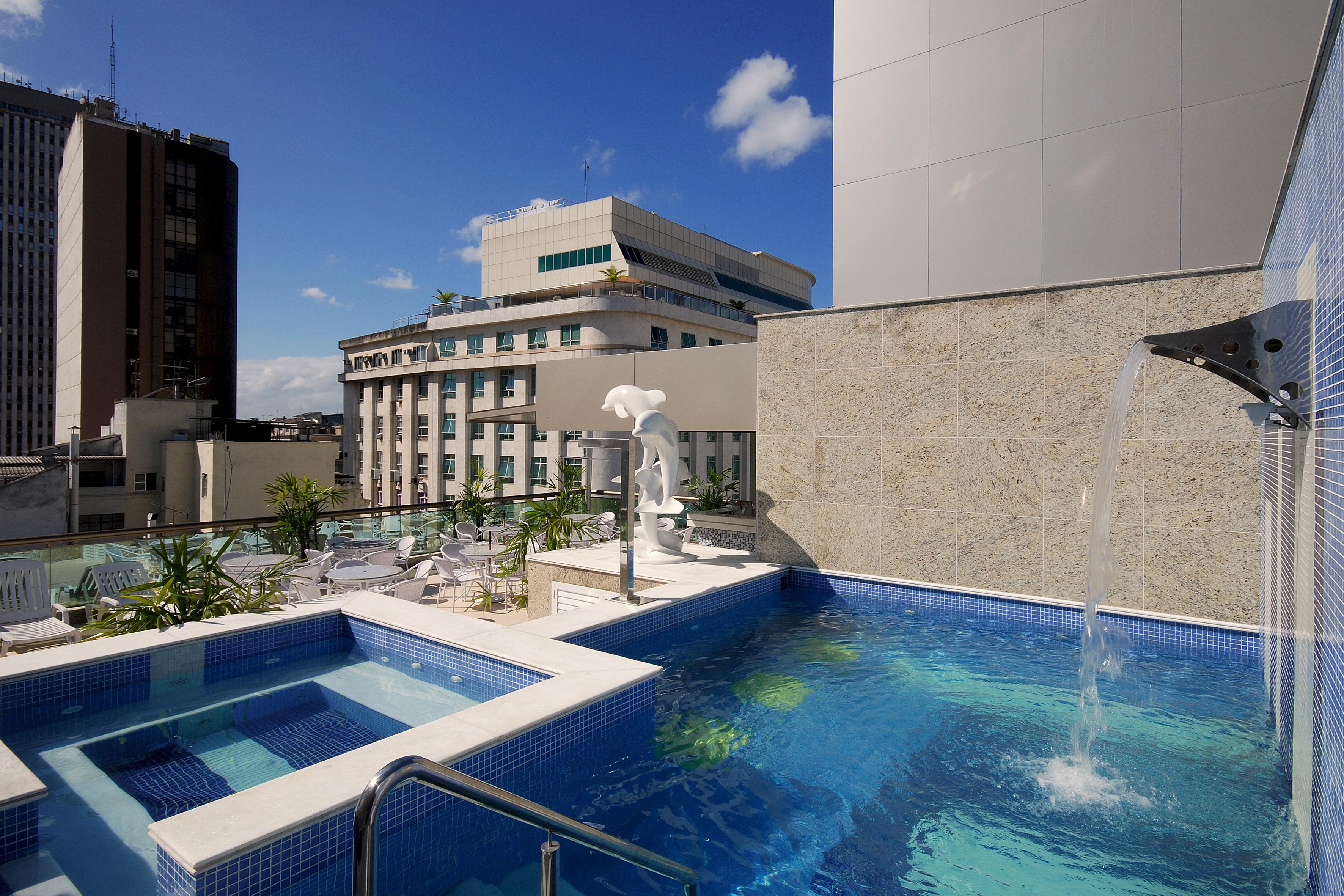 Hotel Atlantico Business Centro Рио де Жанейро Екстериор снимка The photo shows a rooftop area featuring a swimming pool and a spa. The pool is inviting with a clear blue water, and there appears to be a waterfall feature. Surrounding the pool are areas for relaxation, possibly with sun loungers. In the backgroun